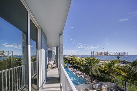 a balcony with a pool and a view of the water and a bridge