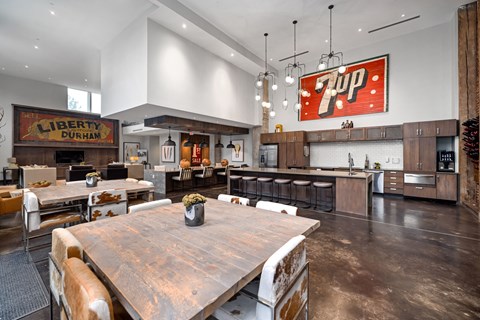 A large wooden dining table is surrounded by chairs in a modern kitchen.