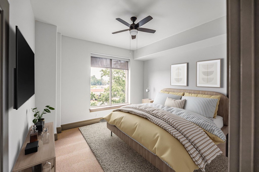 a bedroom with a large window and a ceiling fan