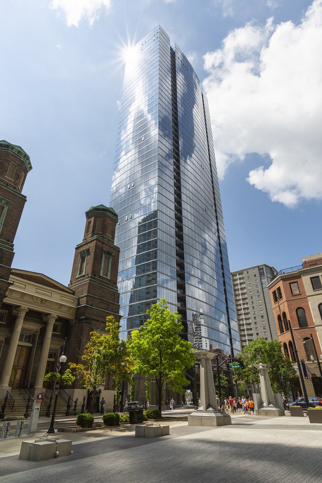 A tall glass skyscraper stands in front of a historic building.