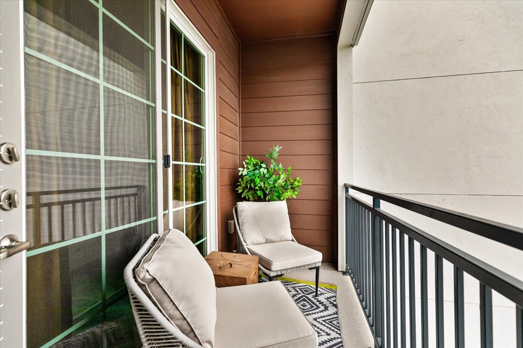 a balcony with two chairs and a potted plant