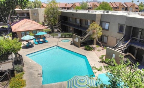 A swimming pool surrounded by a patio area with a table and chairs.