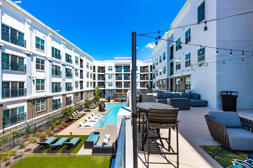 an apartment patio with a pool and lounge chairs