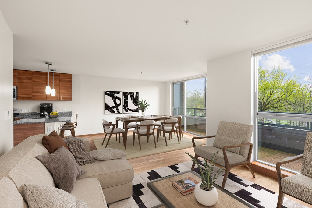 an open plan living room and dining area with a wooden table and chairs and a large window