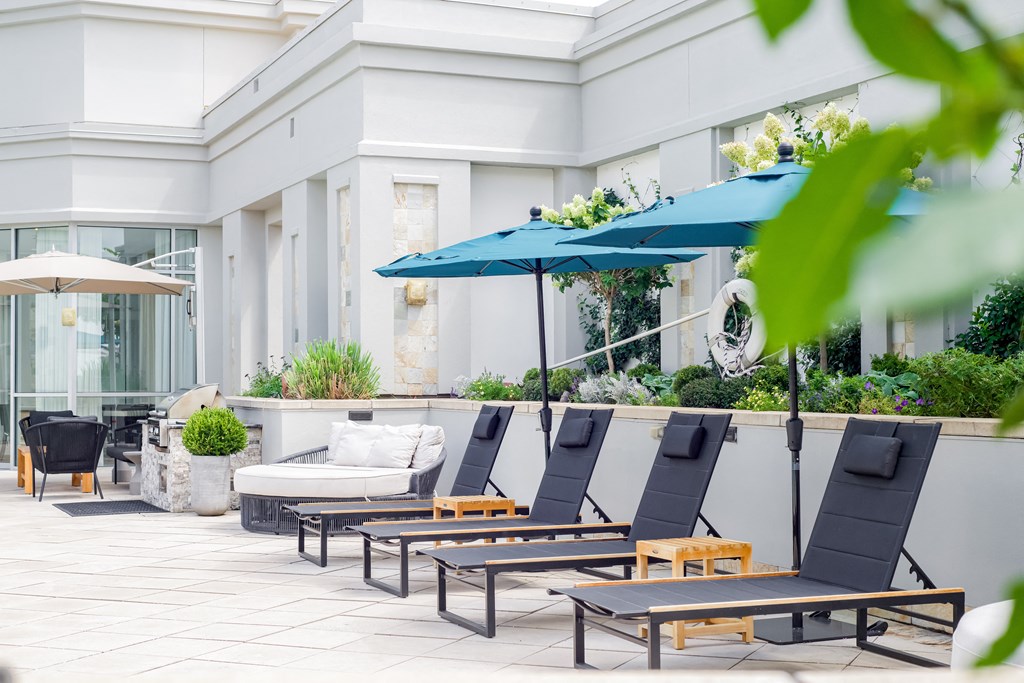 a row of deck chairs with umbrellas in front of a building