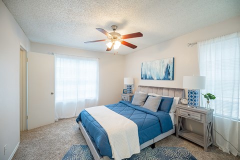 A bedroom with a bed, nightstand, and a ceiling fan.