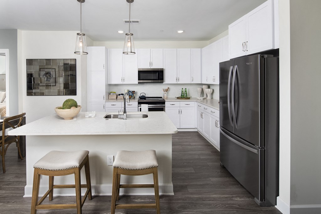 a kitchen with white cabinets and a large island with two stools