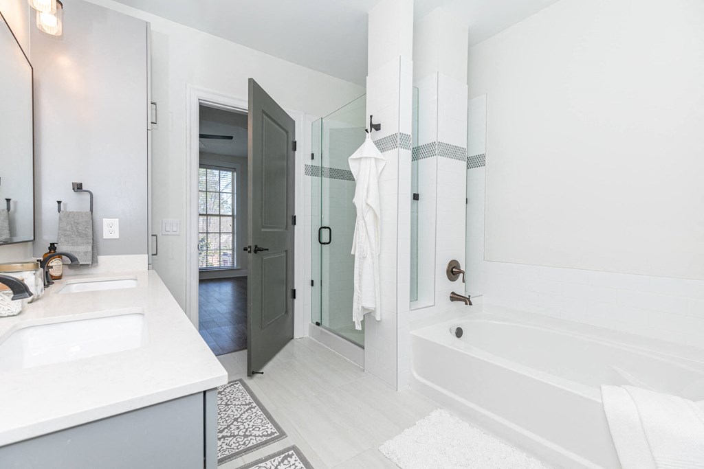 a white bathroom with a tub and a sink and a shower