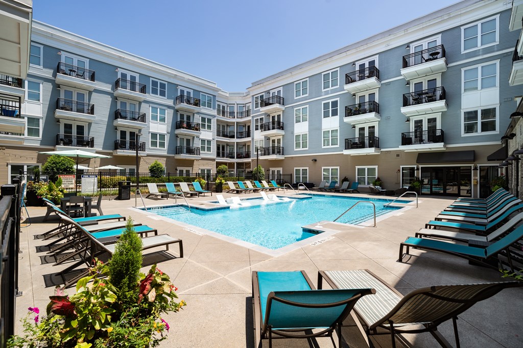 an apartment building with a swimming pool and lounge chairs