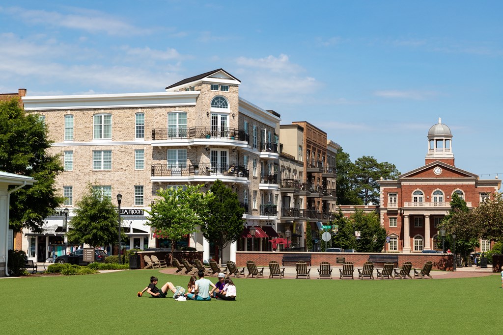 people sitting on the lawn in front of buildings on a sunny day