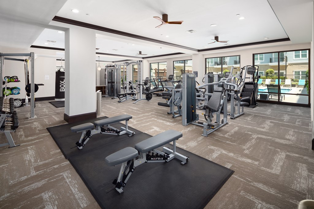 a gym with weights and cardio equipment in a building with windows