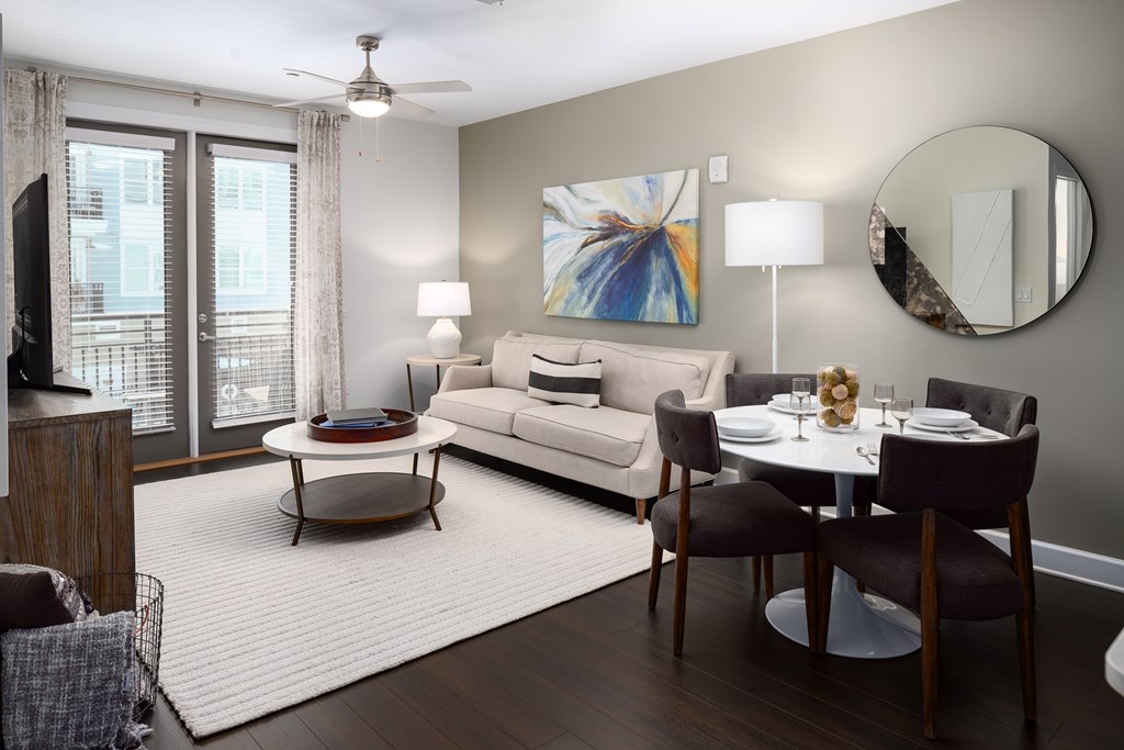 a living room and dining room with a white rug and a couch and a table