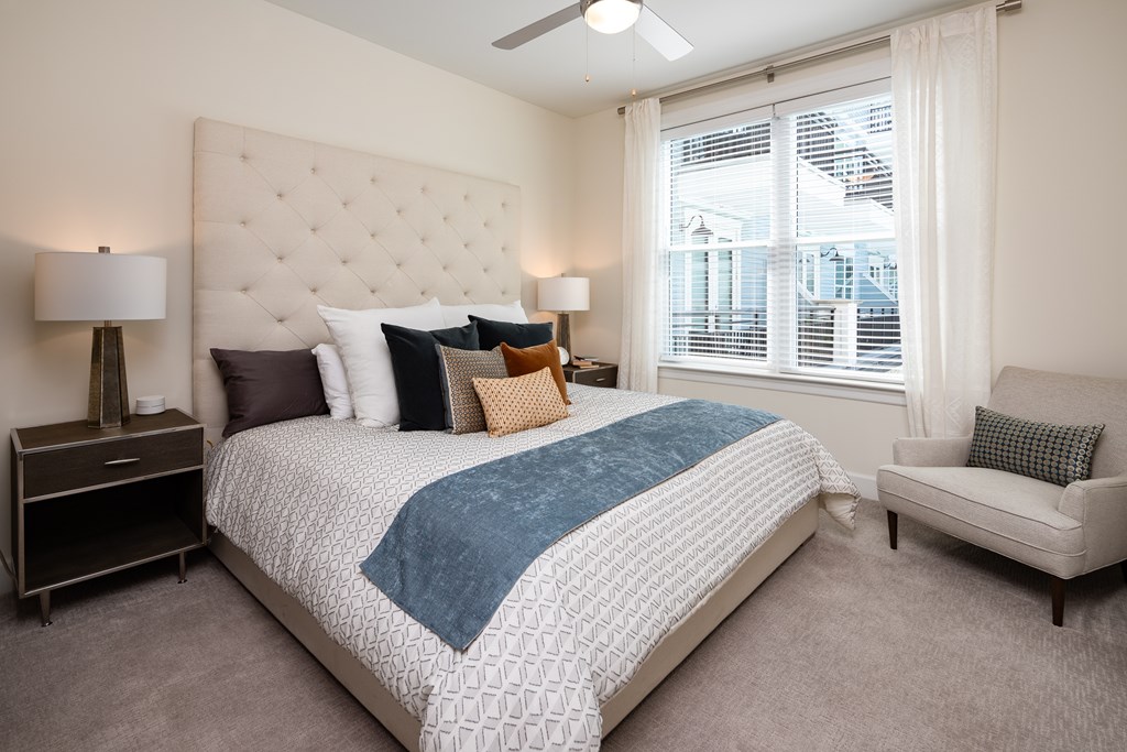 a bedroom with a bed and a chair and a window