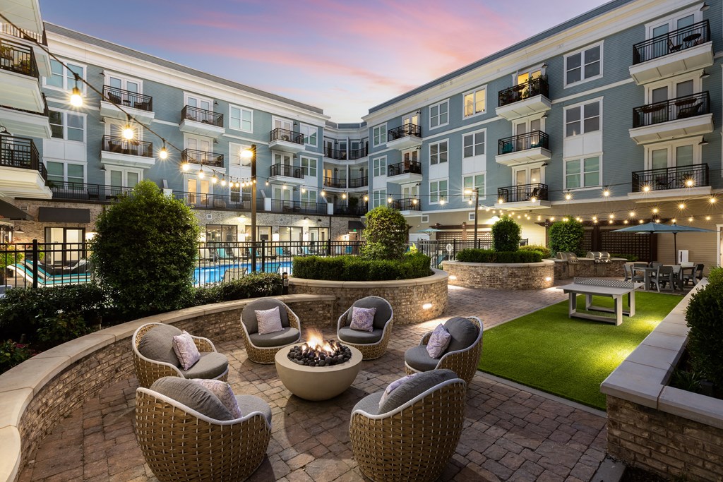 an outdoor patio with chairs and a fire pit at dusk