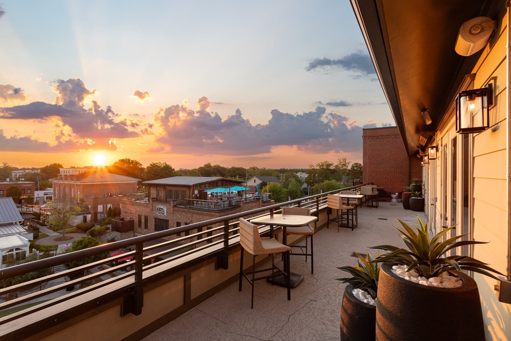 a rooftop terrace with tables and chairs and a sunset