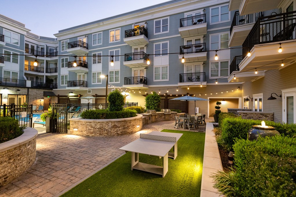 a courtyard with a table and benches in front of an apartment building