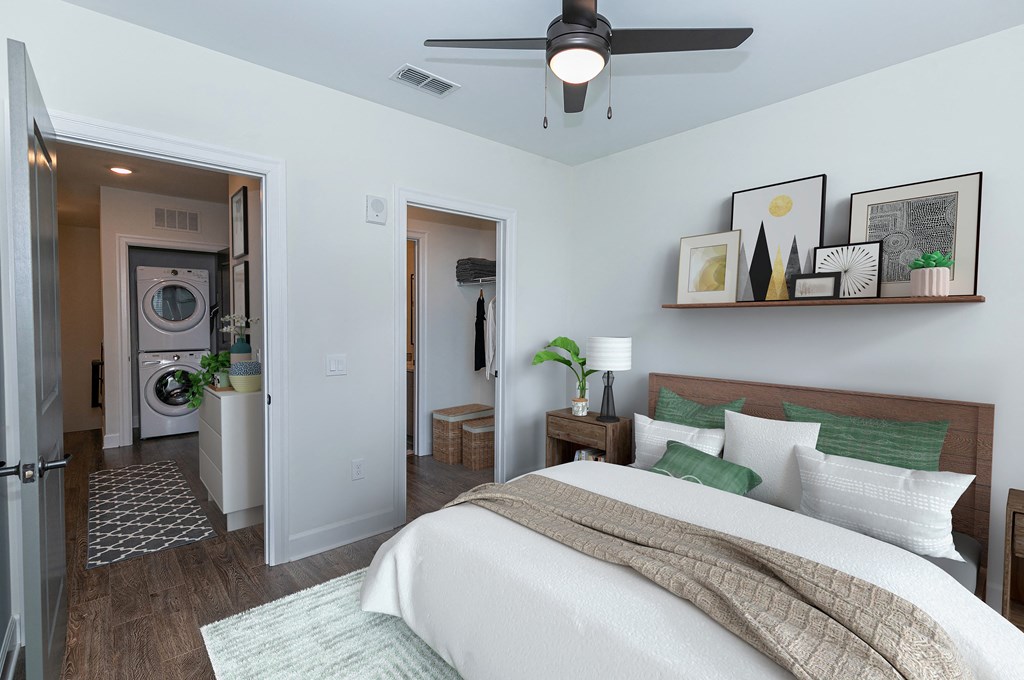 a bedroom with a bed and a ceiling fan and a washer and dryer