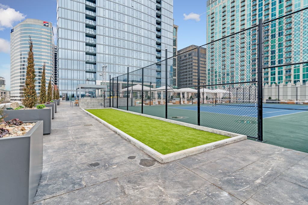 A tennis court surrounded by a fence and buildings.
