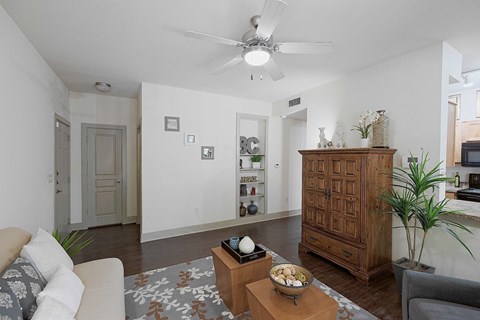 A living room with a white couch, a wooden cabinet, and a rug on the floor.