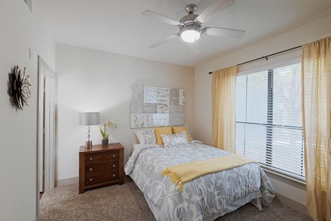 A bedroom with a bed, nightstand, and window.