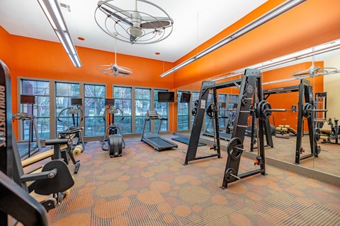 A gym with orange walls and a variety of exercise equipment.