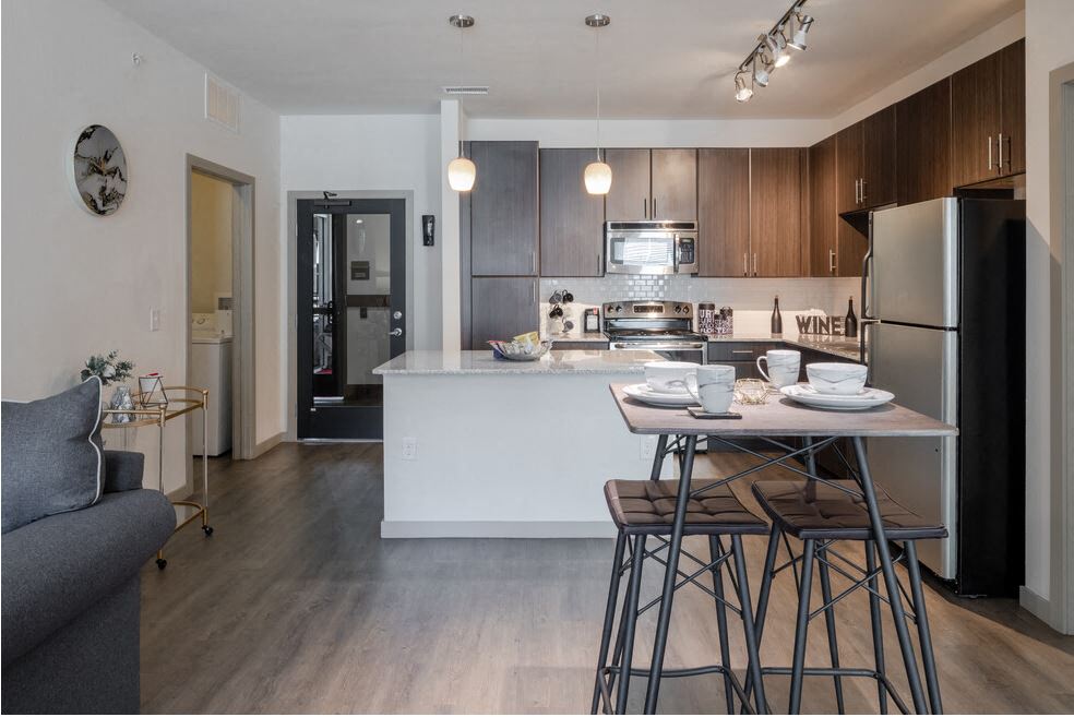 Centro Apartments model kitchen with table, track lights and brown cabinets