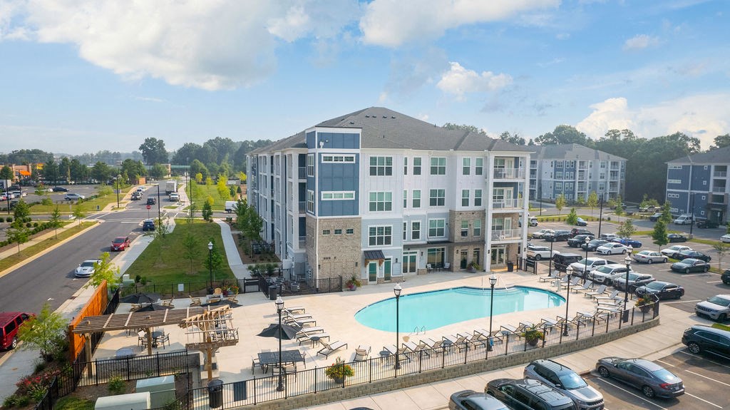 an aerial view of a building with a pool and parking lot