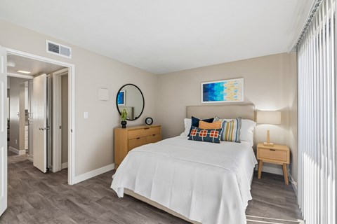 A bedroom with a bed, nightstand, and a mirror on the wall.