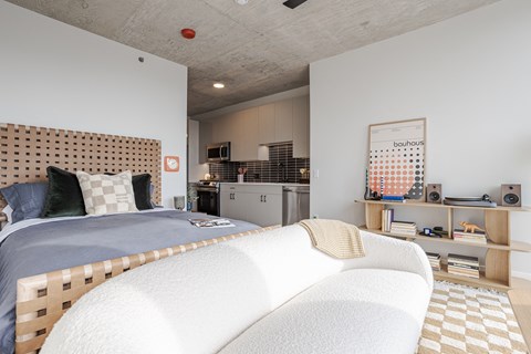 A bedroom with a bed, a couch, and a small kitchenette.