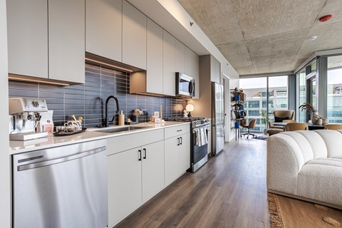 A modern kitchen with a stainless steel dishwasher and white cabinets.