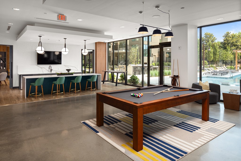 a pool table in a clubhouse with a bar and a swimming pool