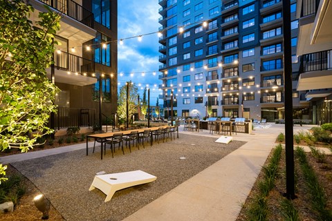a courtyard with tables and chairs in front of a tall building