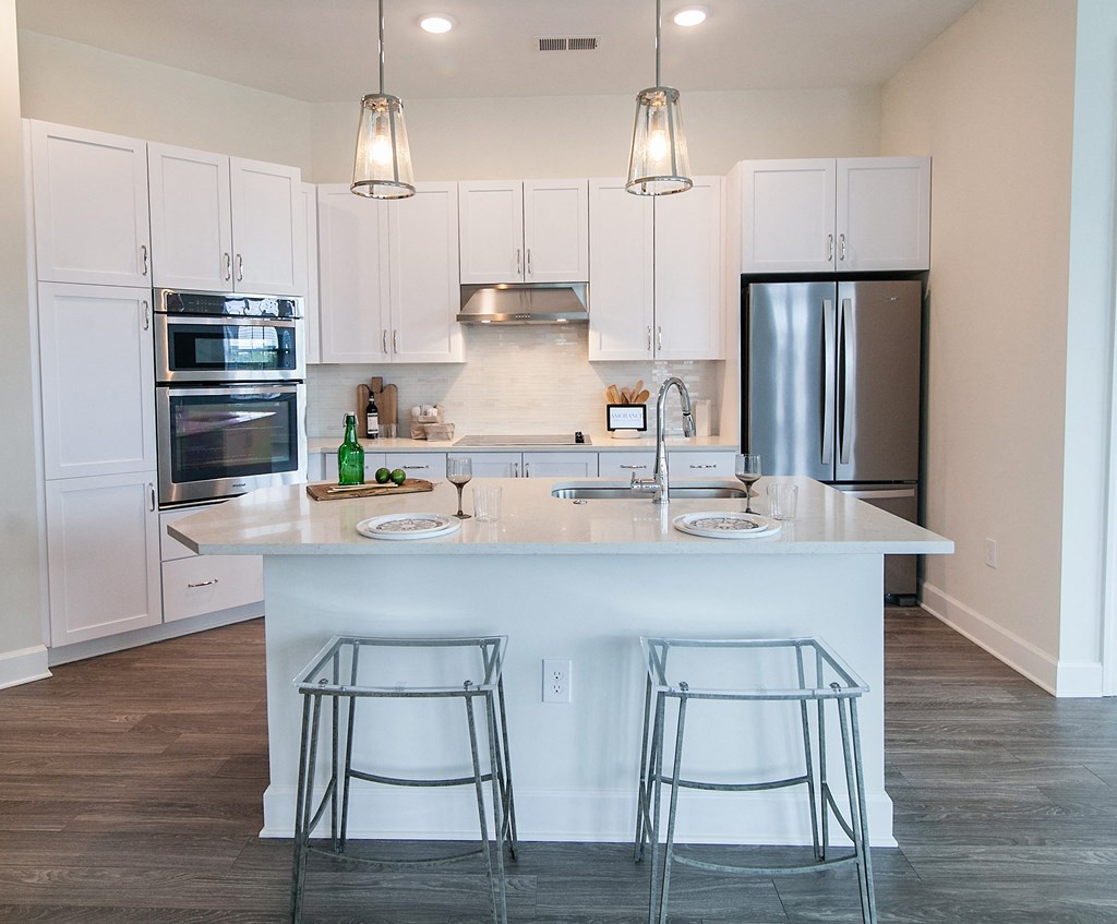 a kitchen with white cabinets and a large island with three bar stools