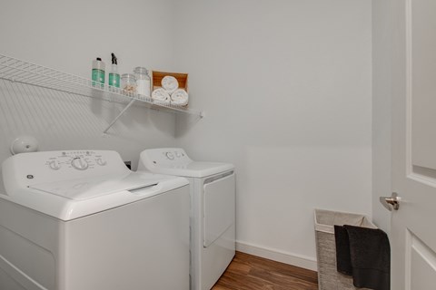 the laundry room has a washer and dryer and a shelf above the was