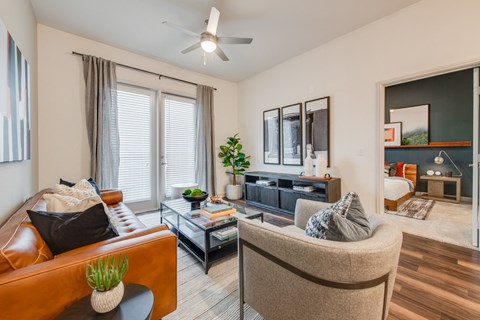 a living room with a couch and a chair and a ceiling fan