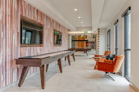 the lobbies with shuffleboard tables and chairs in the clubhouse of a building