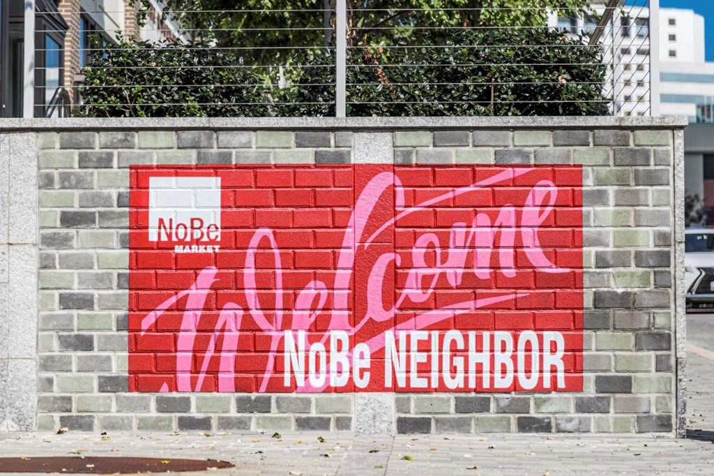 A wall with a Coca Cola logo and the words "NoBe Neighbor" written on it.