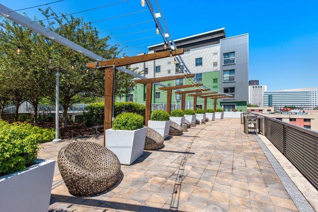 A rooftop patio with a woven chair and a white planter.