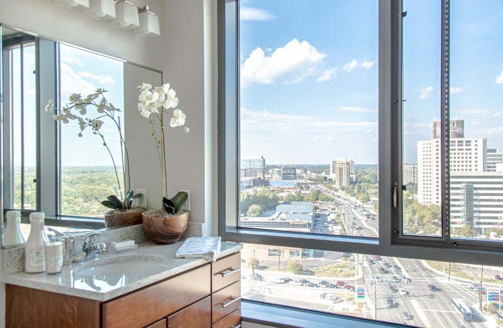 A bathroom with a view of a highway and buildings.