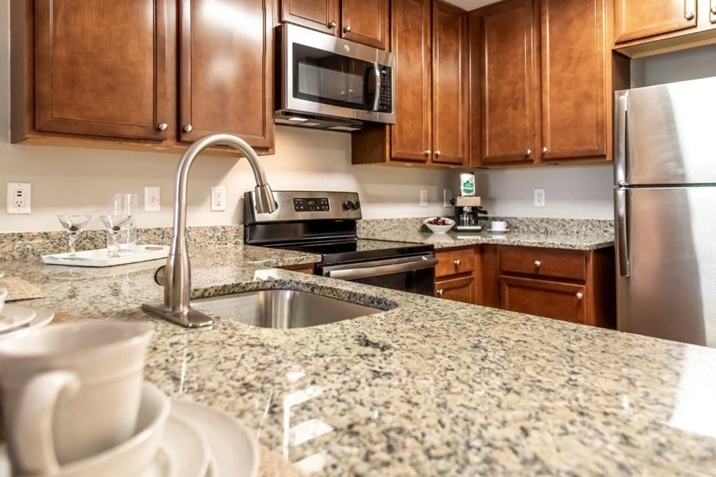 A kitchen with brown cabinets and granite countertops.