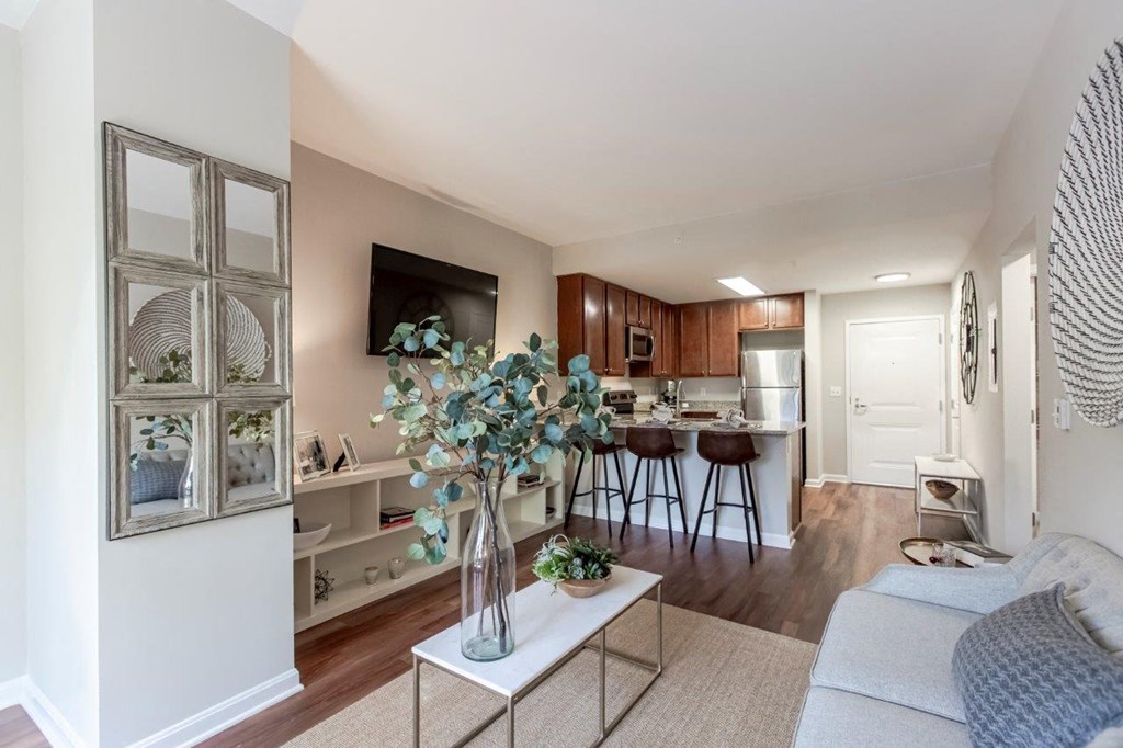 A living room with a white couch and a coffee table with a vase of flowers on it.