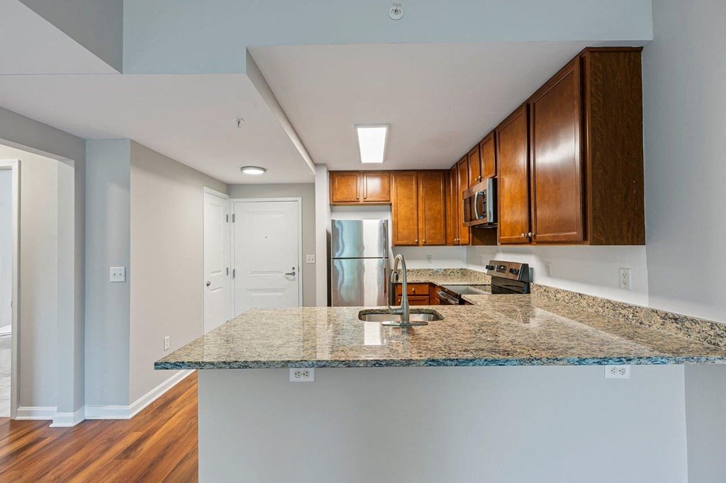 A kitchen with a granite countertop and wooden cabinets.