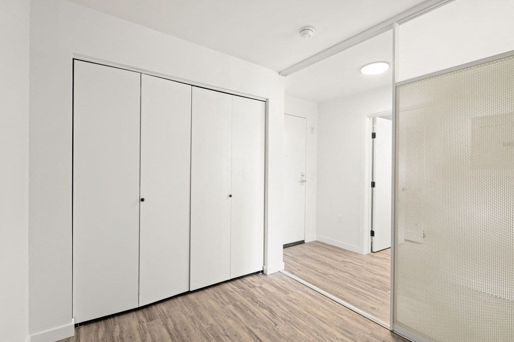 a bedroom with a medium sized white wardrobe and a mirrored closet door