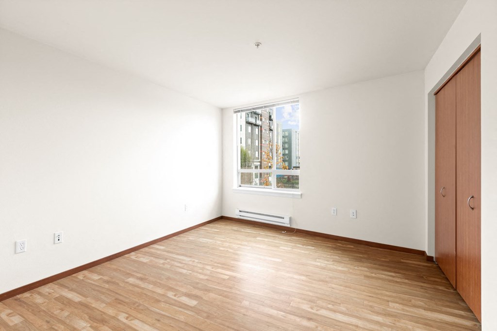 a bedroom with hardwood floors and a large window