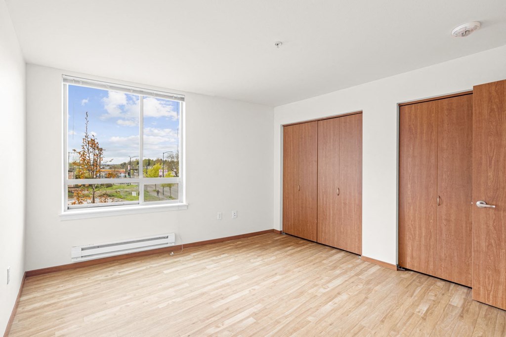 a bedroom with hardwood floors and a large window