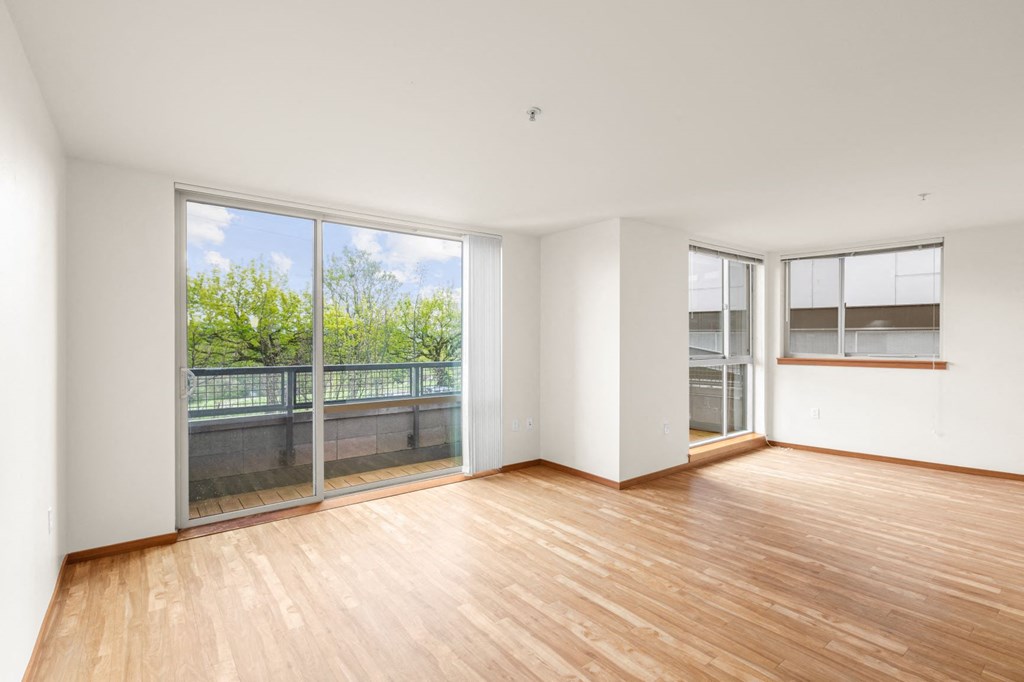 a bedroom with a large window and hardwood floors