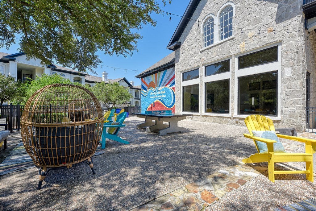 a patio with chairs and tables and a mural on the side of a building