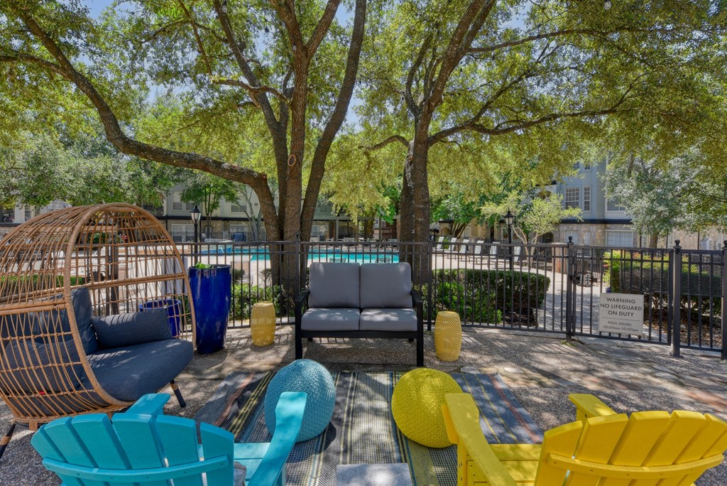 a courtyard with couches and chairs and a pool in the background