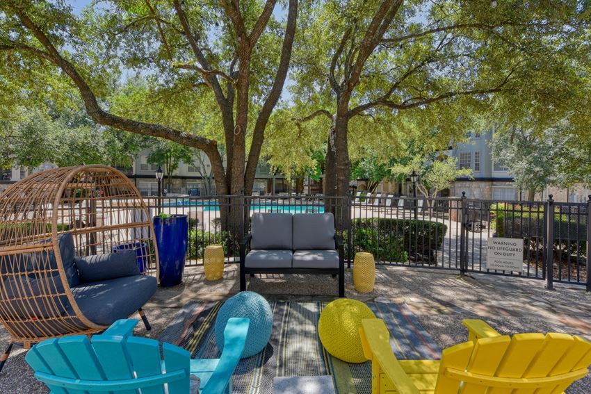 a courtyard with couches and chairs and a pool in the background - Photo Gallery