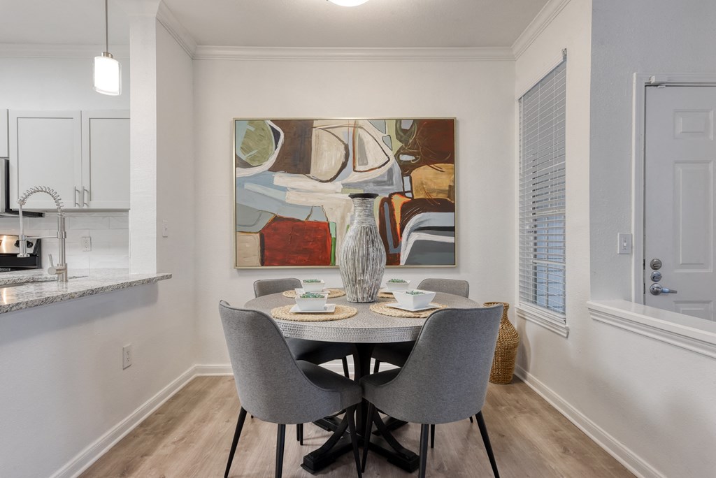 a dining room with a table and chairs and a painting on the wall